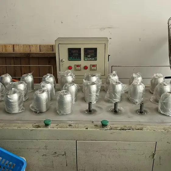 Rows of unfinished stainless steel bottle bodies on a factory line