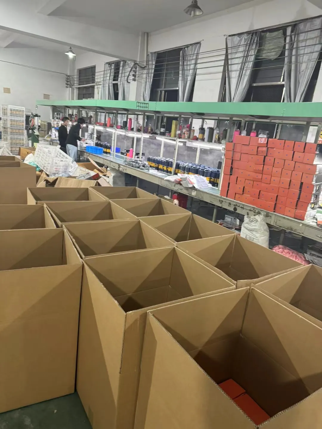Open corrugated cartons arranged beside a drinkware packing line