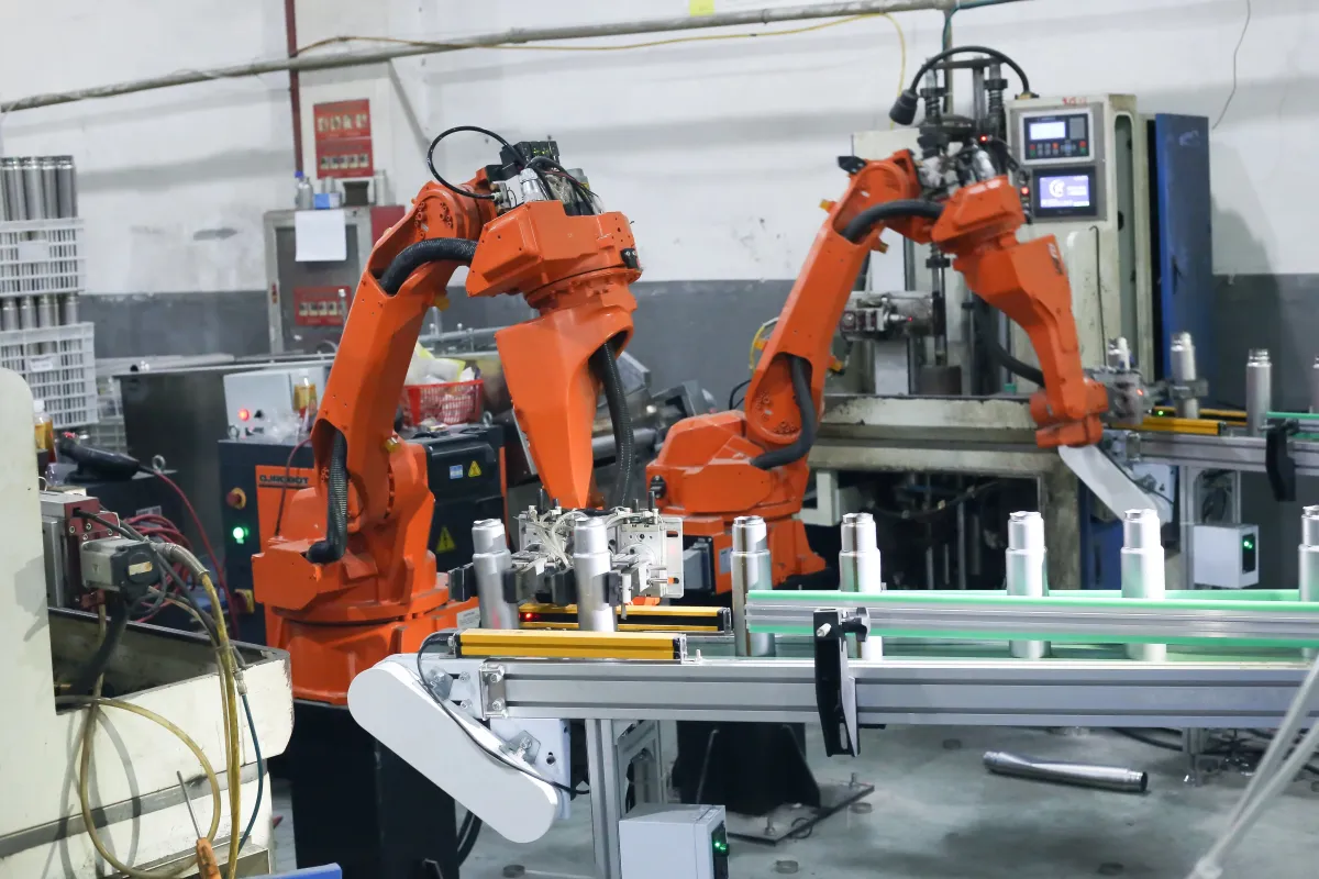 Robotic arms operating at an automated drinkware assembly station