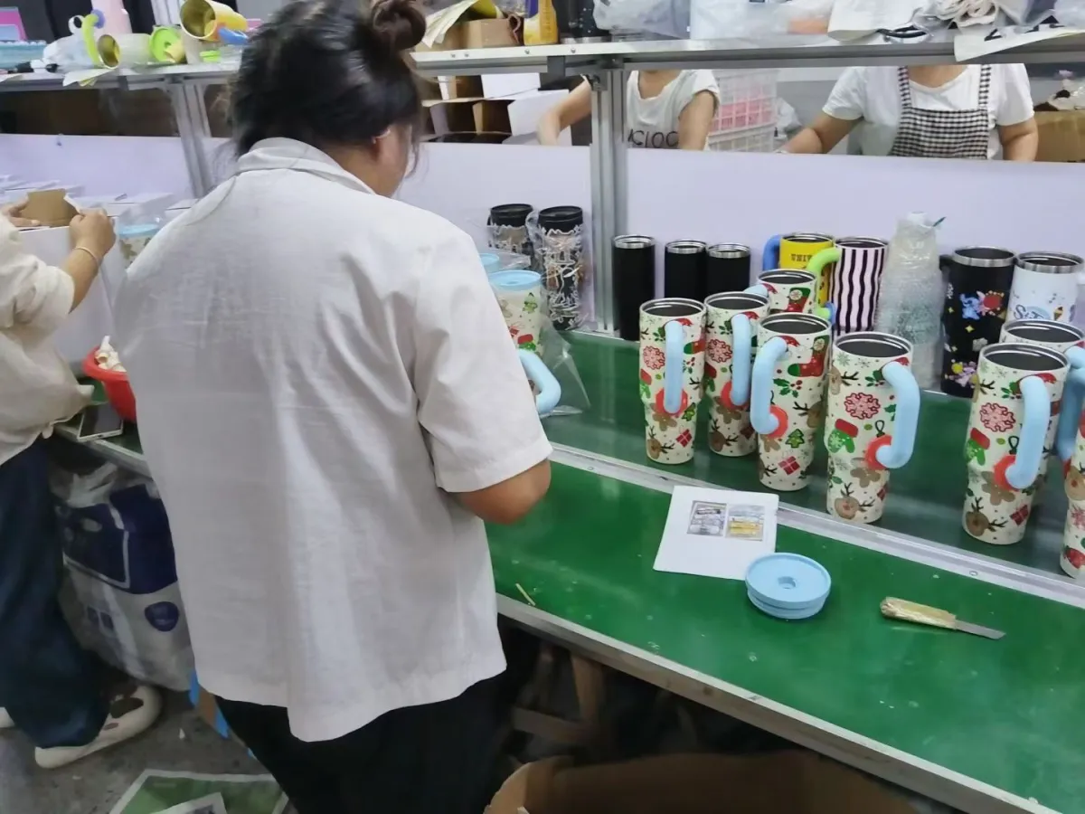 Worker checking printed tumbler designs during production