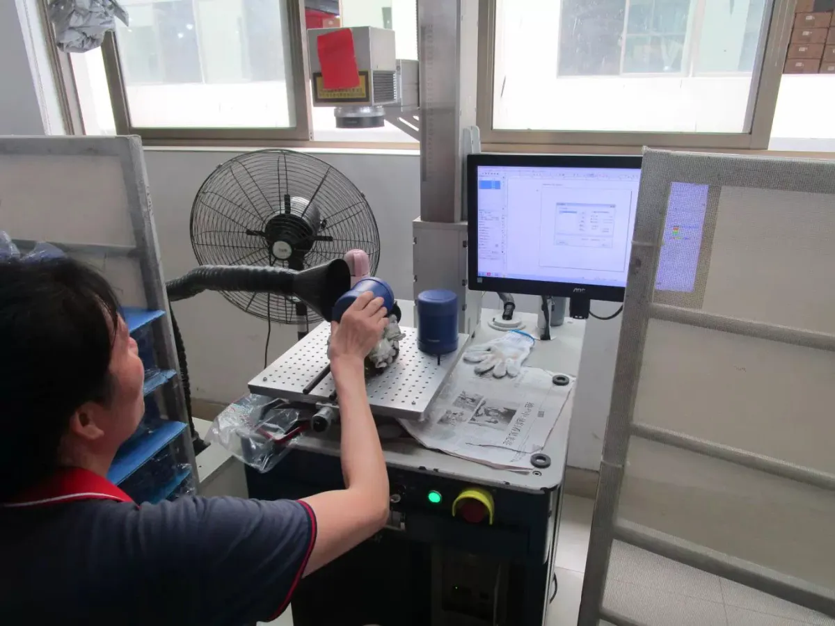 Operator positioning a tumbler beneath a laser marking head at the Bluegreen factory