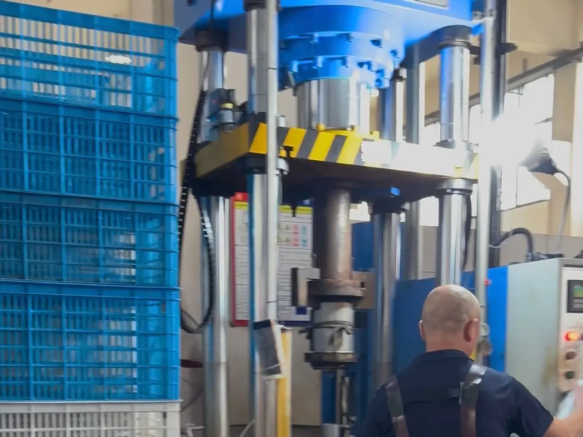 Worker operating a hydraulic press during stainless steel cup body production