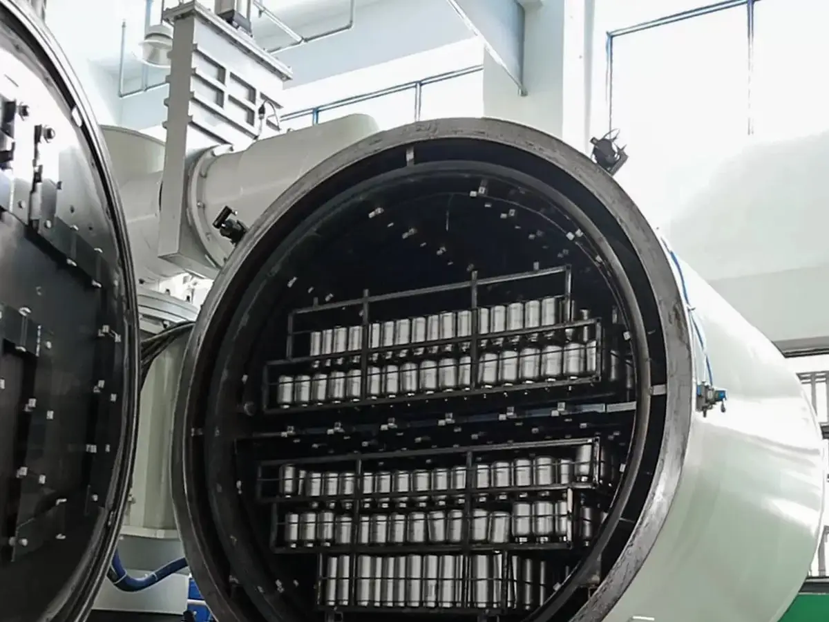 Rows of stainless steel insulated cup bodies loaded into a large factory processing chamber