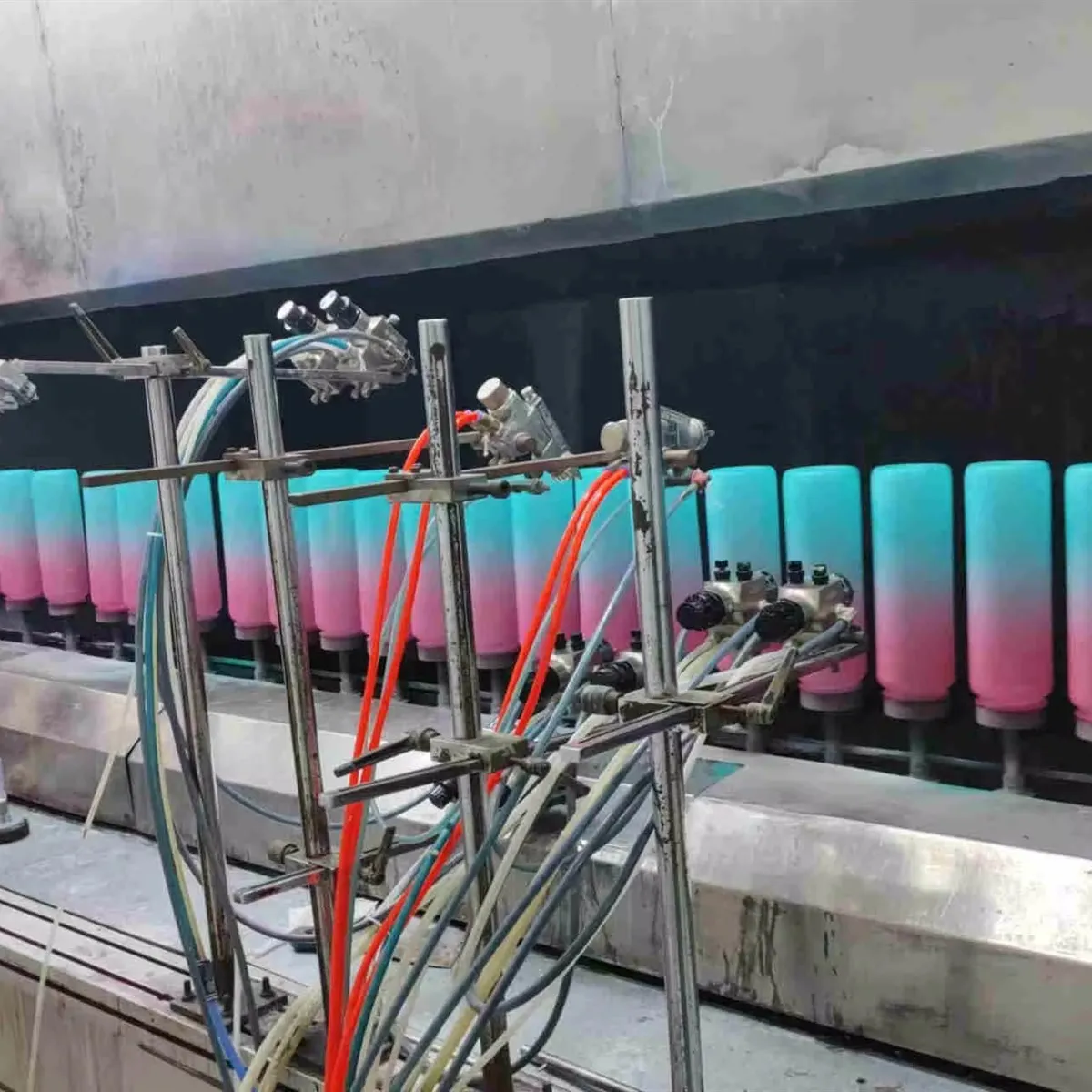 Gradient-coated tumblers moving through a factory spray finishing line