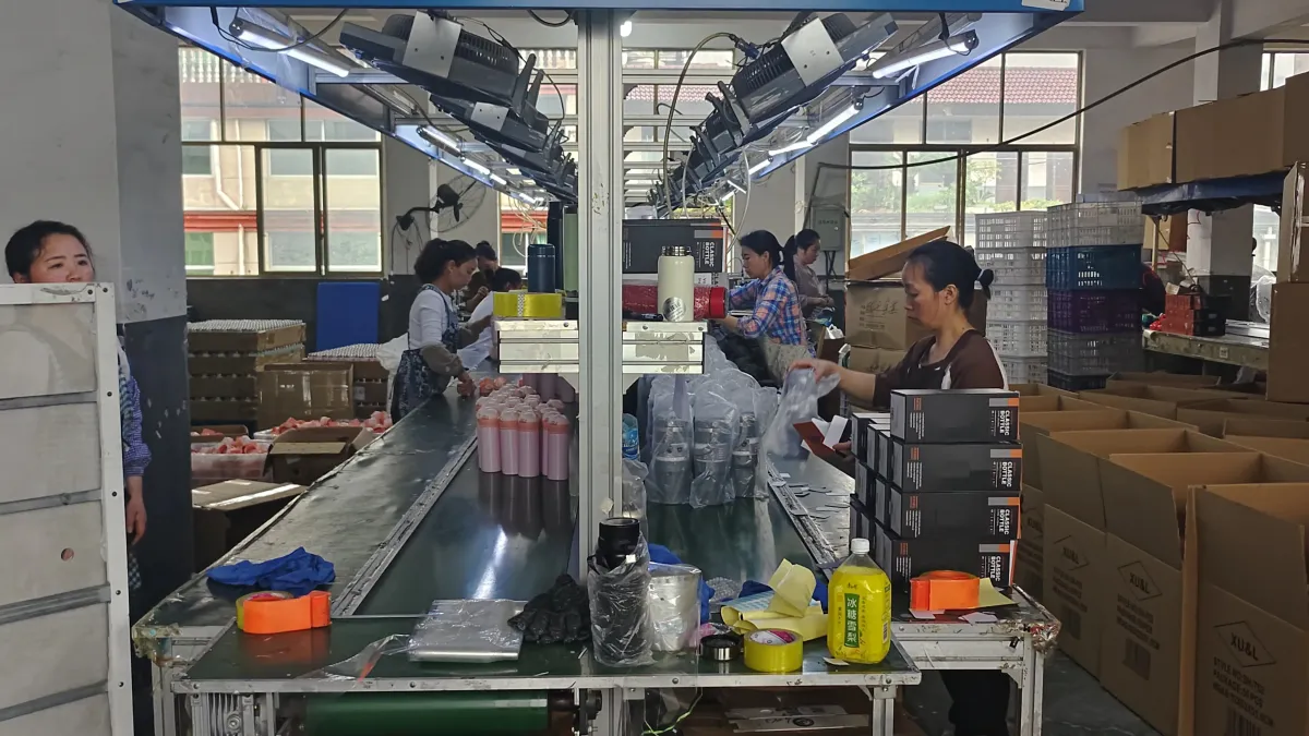 Drinkware assembly line with workers handling lids and tumbler components