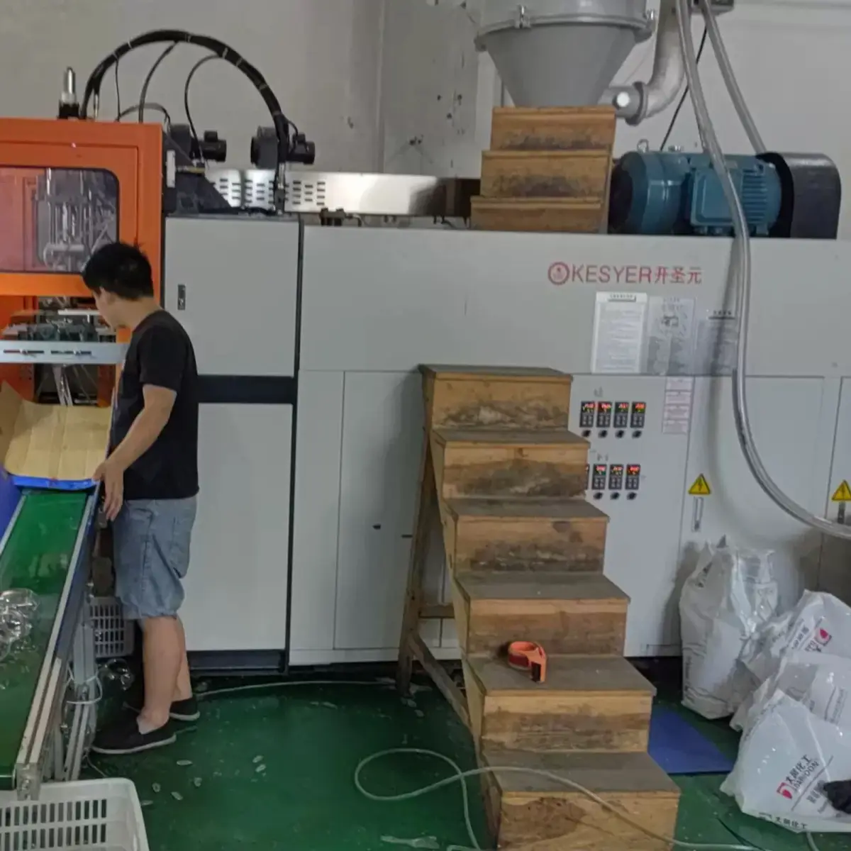 Operator monitoring an injection molding machine used for plastic component production