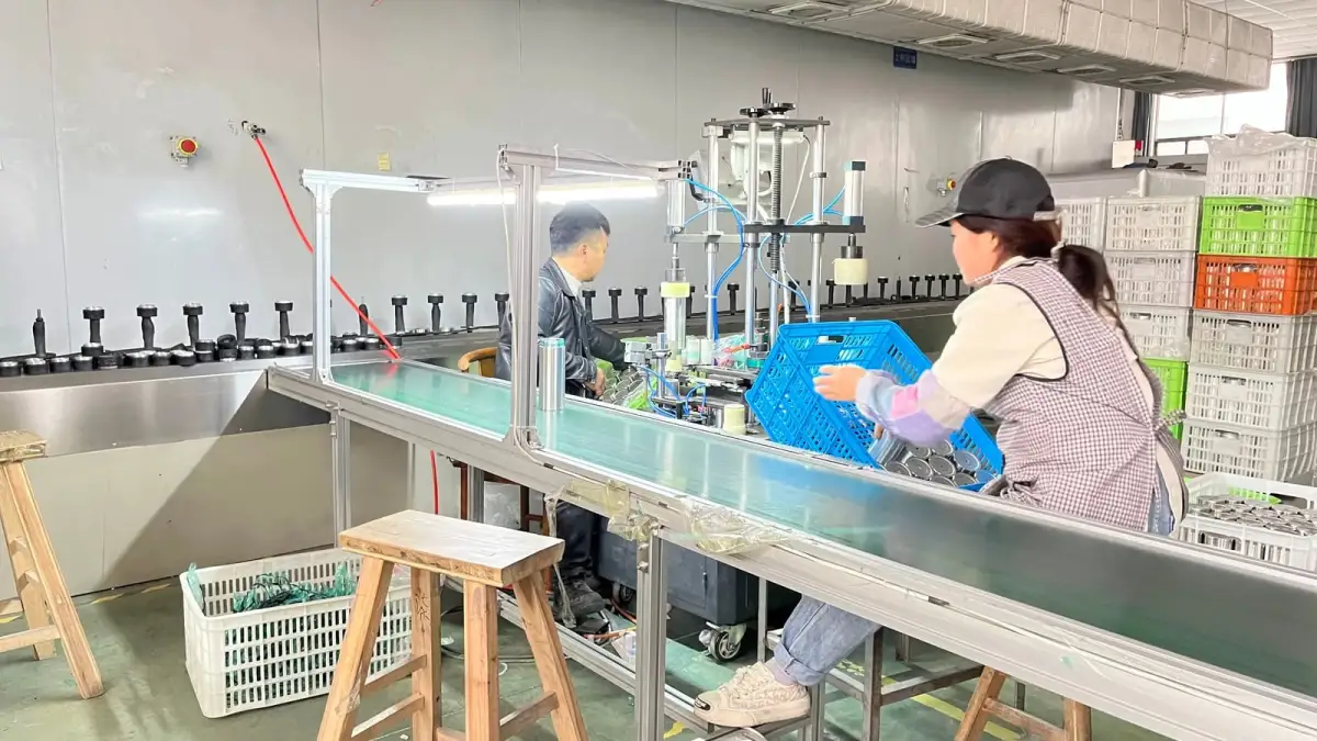 Workers assembling drinkware components on a factory production line