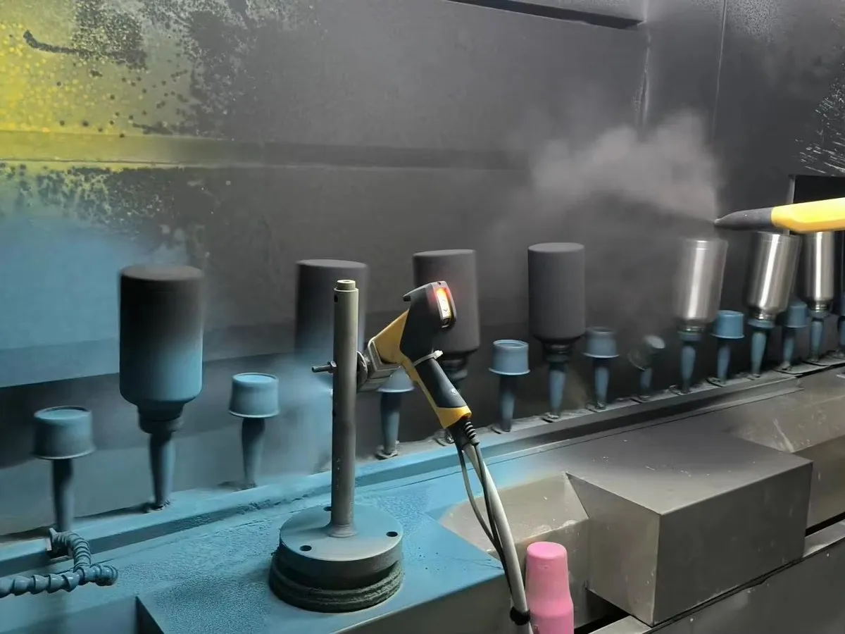 Stainless steel tumbler bodies on fixtures inside a drinkware spray finishing booth
