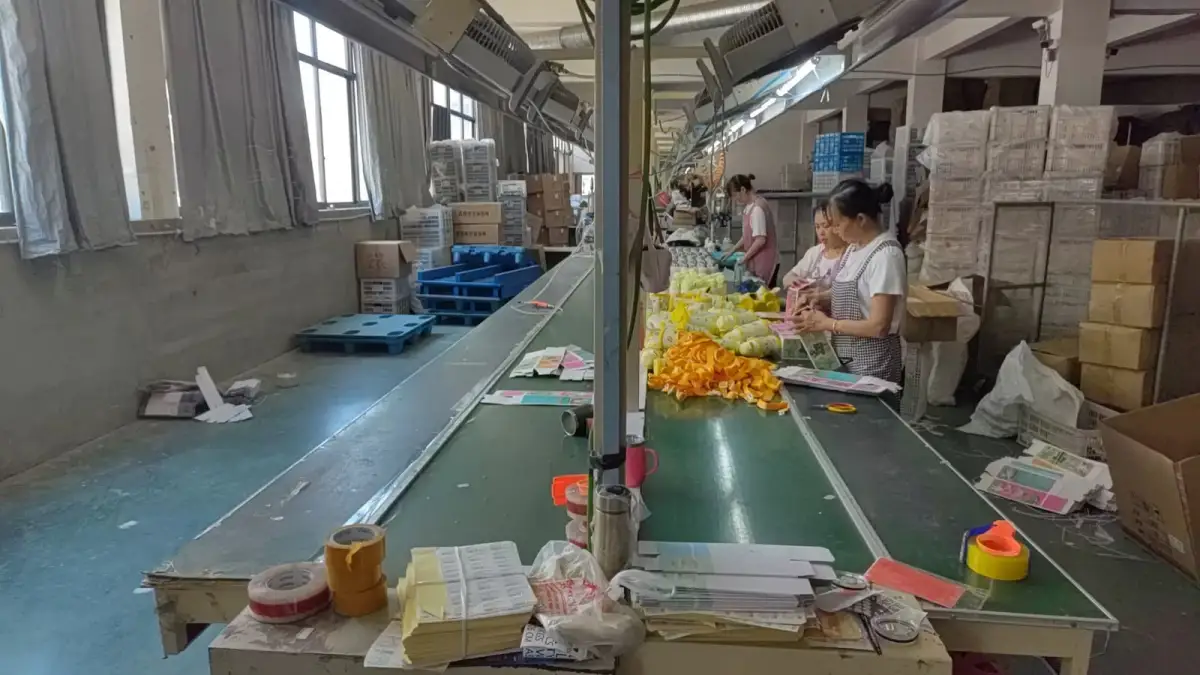 Workers sorting molded plastic components beside a factory conveyor line