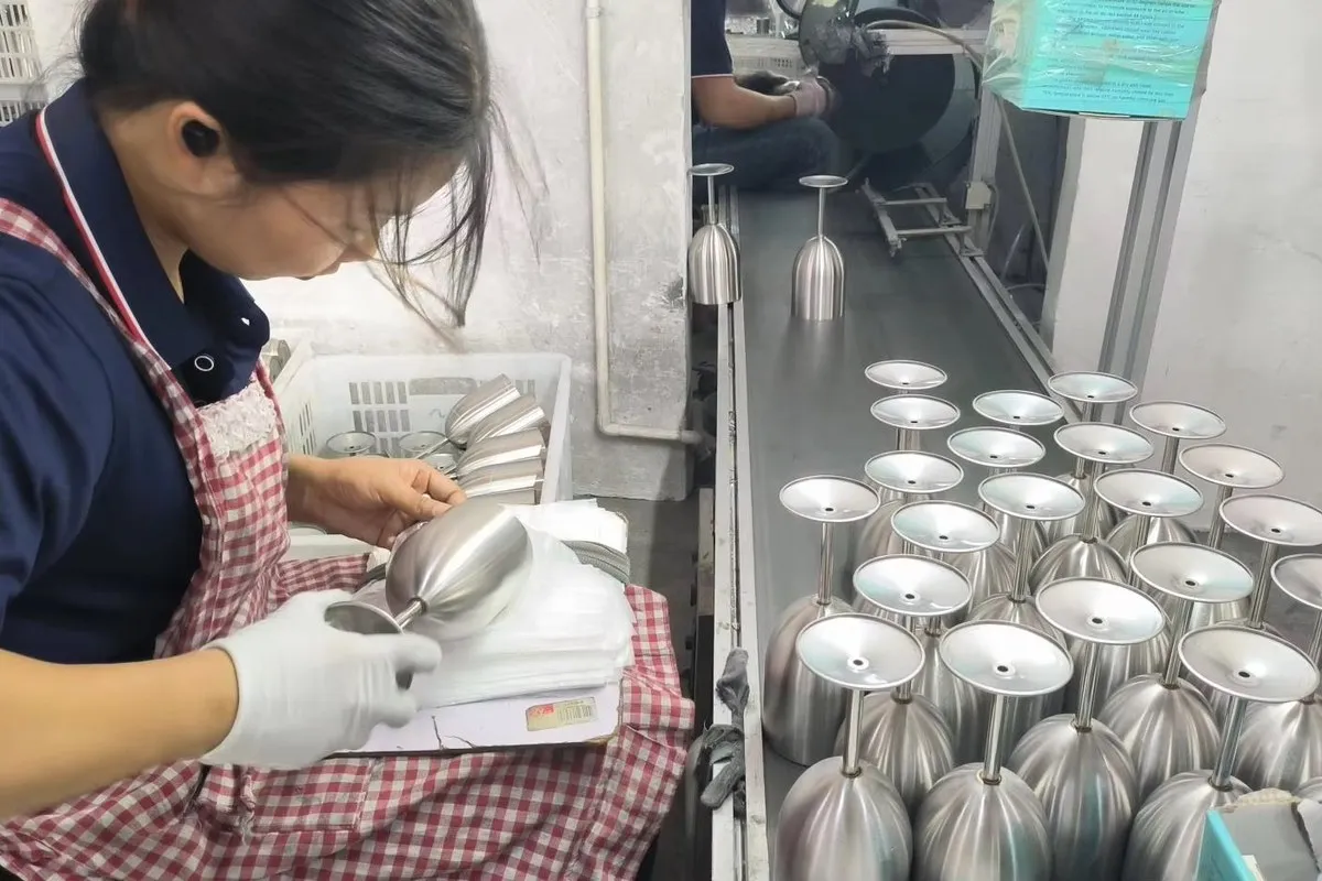 Worker checking unfinished stainless steel cup bodies during production