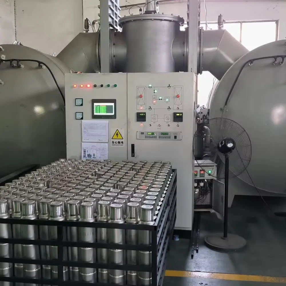 Rows of stainless steel insulated cup bodies staged in front of a twin-chamber vacuum processing system