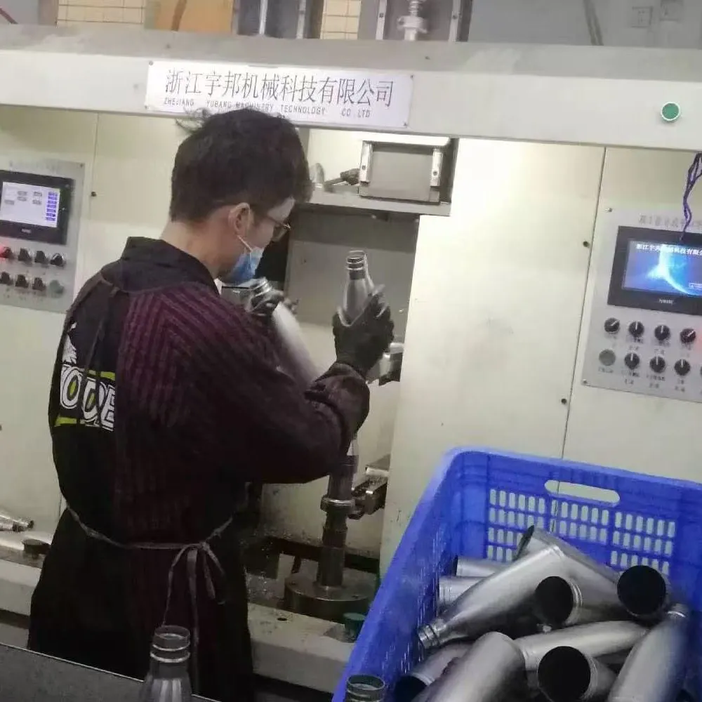 Worker checking an unfinished stainless steel insulated bottle body at a production station