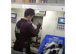 Worker checking an unfinished stainless steel insulated bottle body at a production station