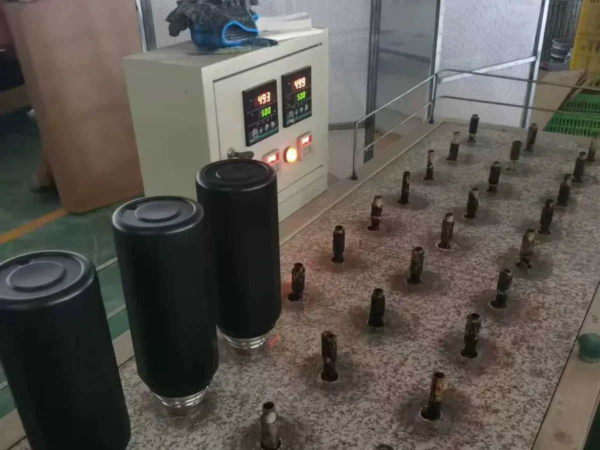 Black insulated tumbler bodies positioned upside down on a temperature-controlled factory fixture