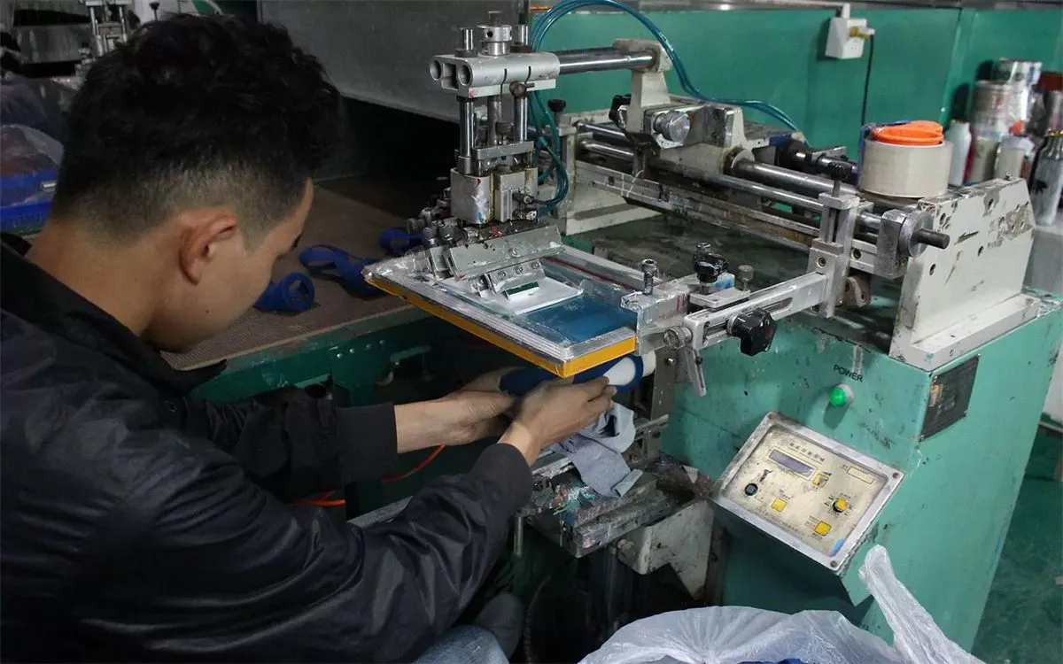 Operator setting up screen printing for a custom logo on drinkware