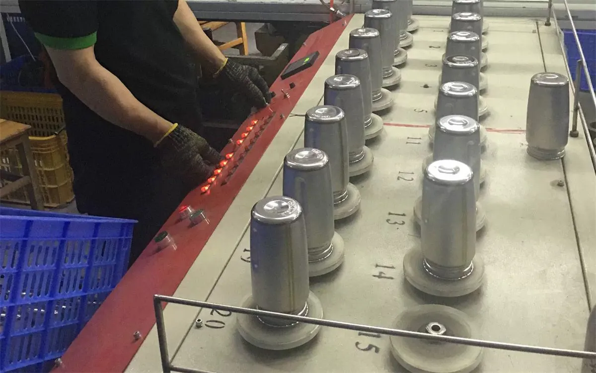 Worker checking unfinished stainless steel cup bodies on a production line