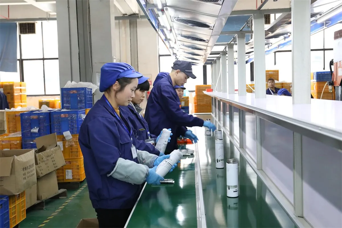 Workers inspecting drinkware units along a factory production line