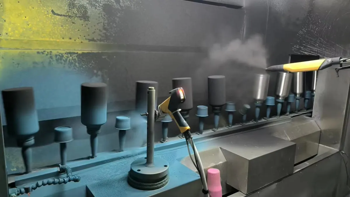 Metal tumbler bodies mounted on rotating fixtures inside a coating booth