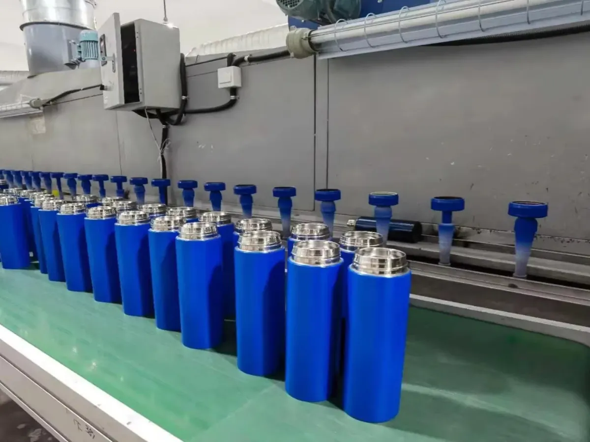 Blue coated tumbler bodies moving through a factory production line