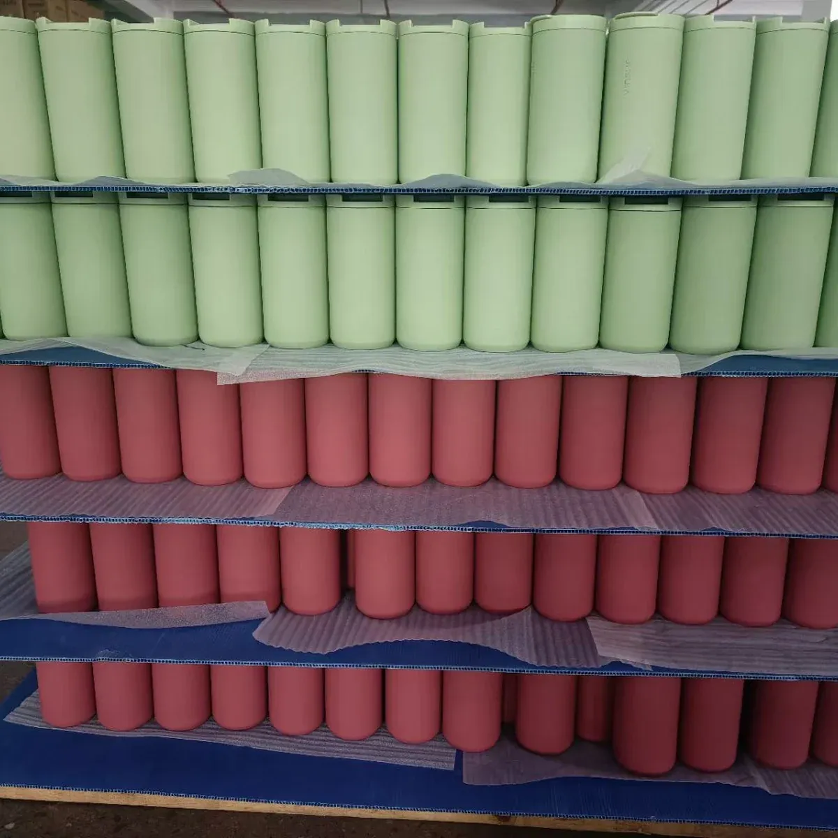Green and pink tumbler bodies arranged in separate factory batches