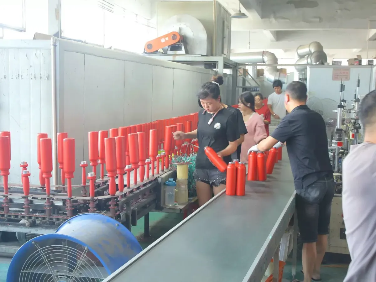 Workers monitoring red cup bodies on a factory finishing line