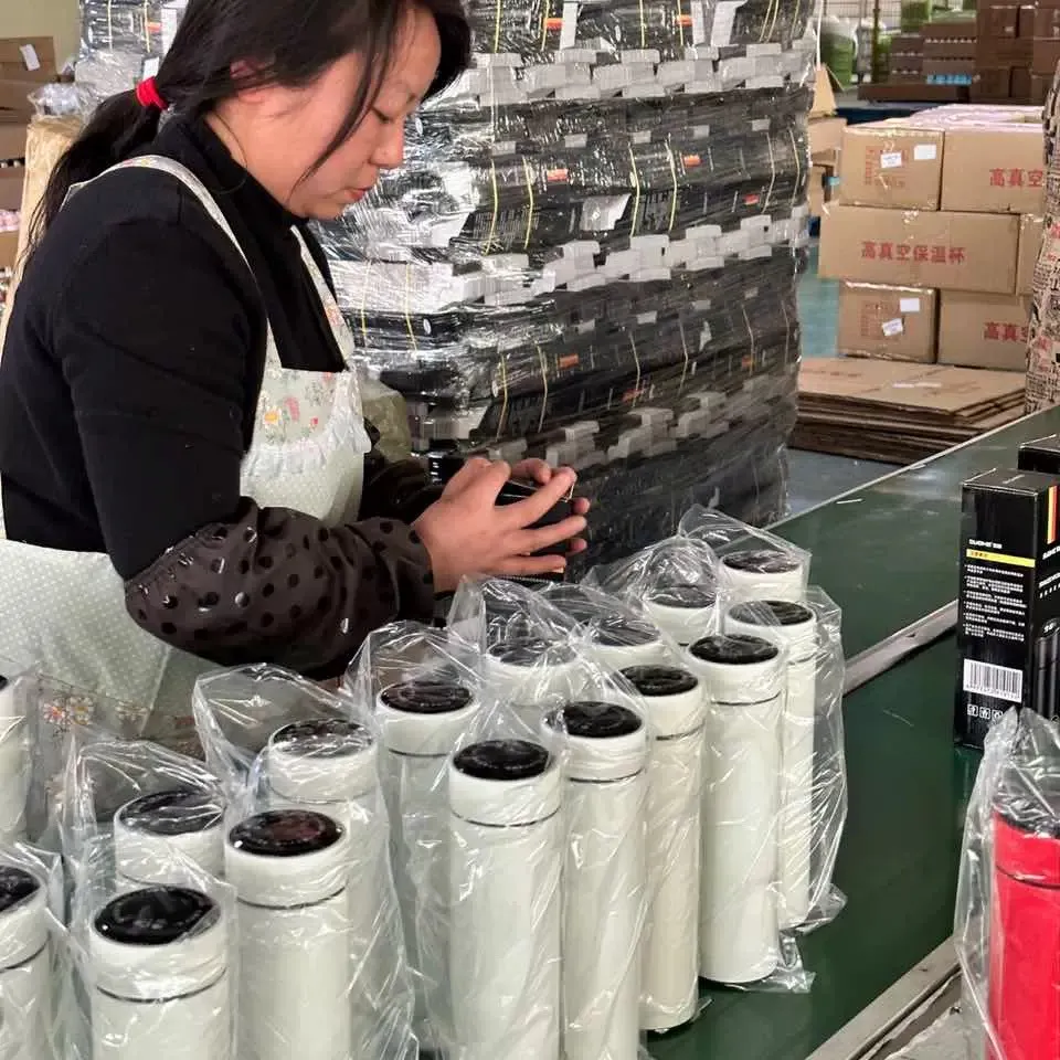 Worker checking a lid component beside finished insulated bottles before packing