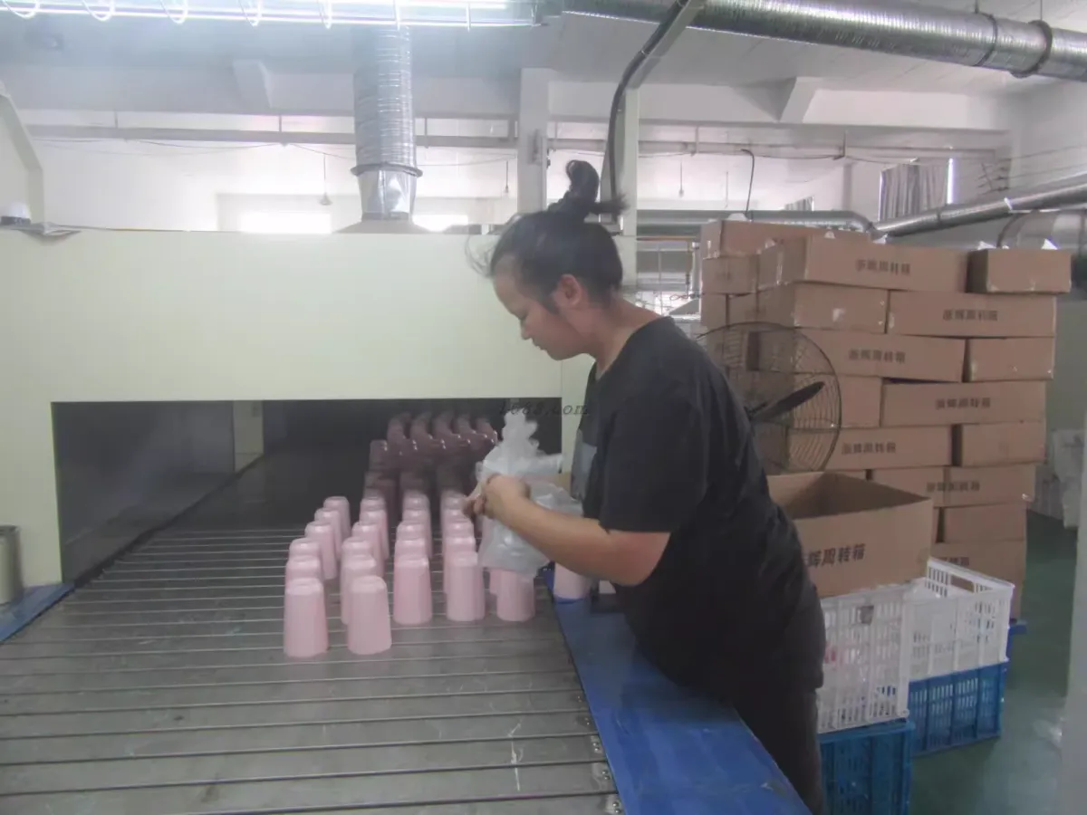 Worker arranging finished pink insulated bottles during production inspection