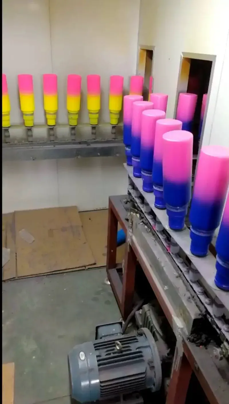 Pink yellow and blue gradient-coated tumbler bodies on a finishing line