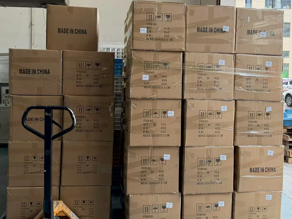 Packed drinkware cartons stacked beside a manual pallet truck