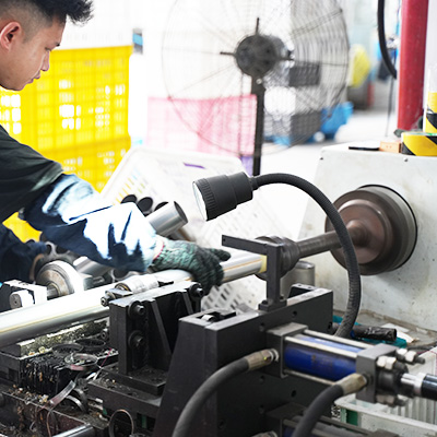 Worker machining a stainless steel drinkware component on a lathe