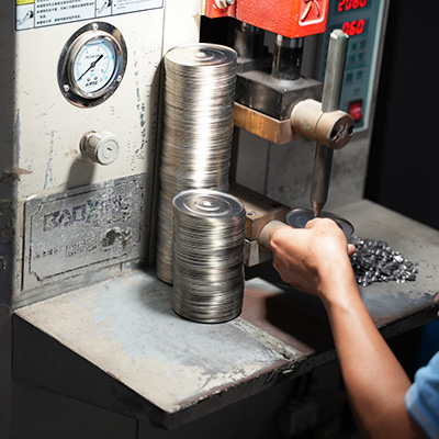 Worker processing small metal components for drinkware